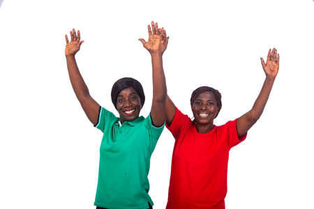 beautiful women in color t-shirt standing on white background showing victory gesture laughing.の写真素材