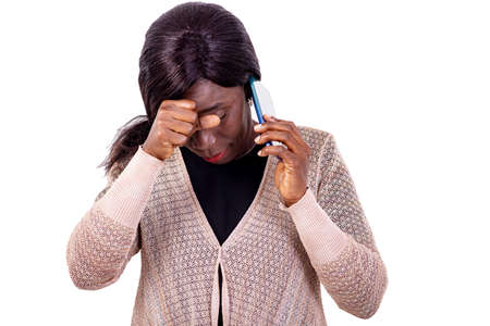 a beautiful woman standing on white background talking on the cellphone while thinking.の写真素材