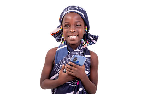 cute little girl wearing traditional African loincloth and holding mobile phone while smiling at camera.の写真素材