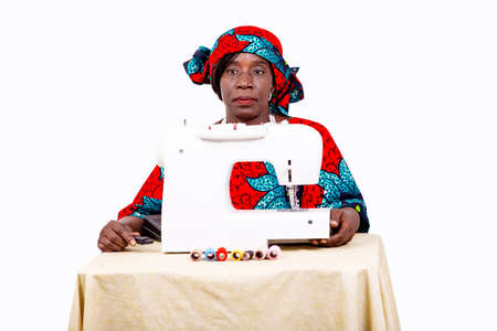 portrait of a beautiful mature woman seamstress sitting in her workshop near her sewing machine.の写真素材