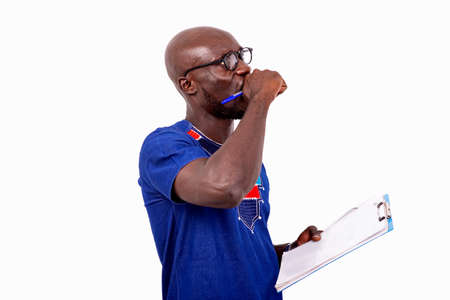 portrait of a young businessman with hand over mouth thinks and holds document on clipboard.の写真素材