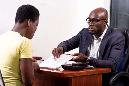 portrait of male insurance agent showing to client for signing document on clipboard in office.の写真素材