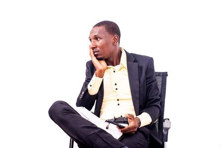 portrait of a businessman sitting on a chair with hand on cheek looking sideways.