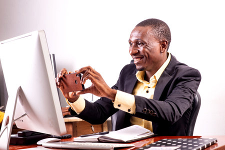 young happy businessman sitting at desk and working with laptop computer while smiling.