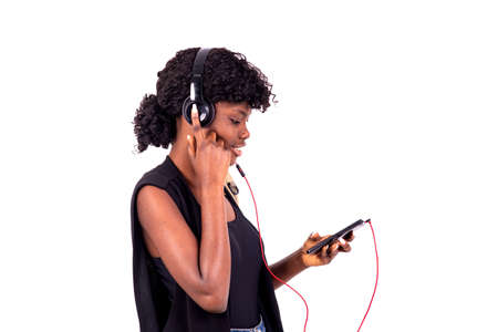 young student with backpack standing on white background listening to music using cellphone and headphones smilingの写真素材