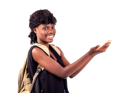 young student girl carrying backpack, with empty hands showing something smiling.の写真素材