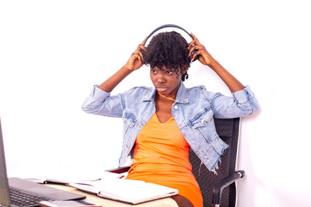 young student sitting in a room adjusting her headphones.