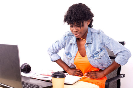 young sick student girl sitting in front of laptop suffering from stomach pain.