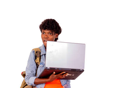 beautiful student girl wearing a backpack amazed holding a laptop.の写真素材