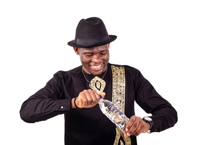 a handsome businessman in embroidered shirt standing over white background opening a bottle of water smilingの写真素材