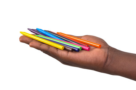 cropped view of a young man's hand holding colored pencils.