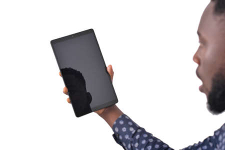 a young bearded man standing over white background looking at a tablet with a stunned lookの写真素材