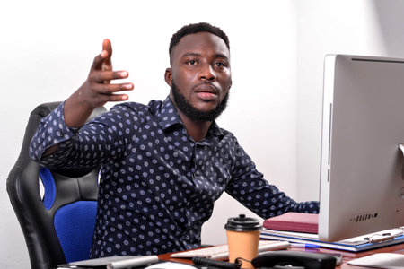 portrait of a young businessman sitting in front of the laptop in his office and gesturing with his...