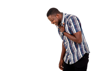 portrait of a handsome young man standing against a white background and laughing with his hand on...