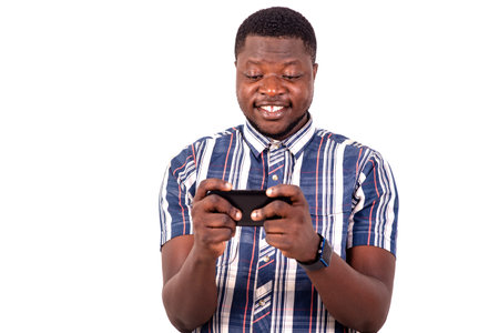 a young man in a short sleeved shirt standing on white background playing games on mobile phone,...