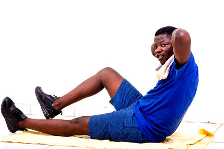 portrait of a sporty young man in sportswear doing a reverse plank with one leg raised on the floor at home.の写真素材