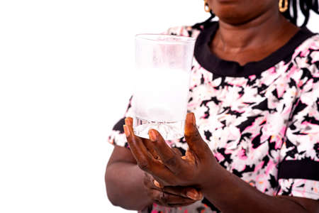 portrait of a sick mature woman wearing optical glasses and putting an effervescent tablet in a glass of water.の写真素材