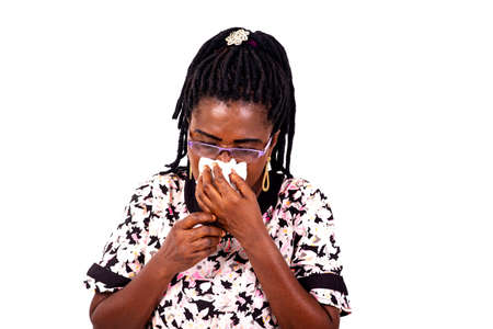 portrait of a beautiful sick adult woman sneezing in a white tissue.の写真素材