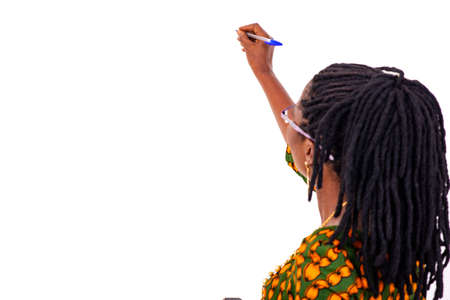 a beautiful mature businesswoman in traditional attire standing in a room writing on chalkboard.の写真素材