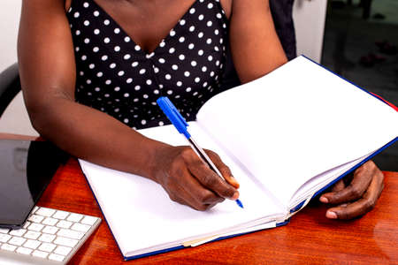 portrait of an adult businesswoman sitting at the desk and writing in the notebook.の写真素材