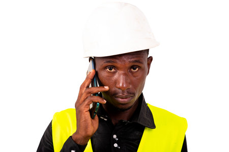young man engineer wearing green vest and safety helmet while talking on mobile phone.