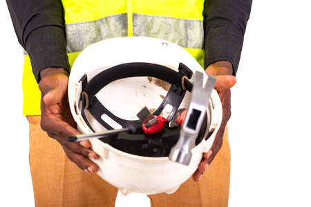 hands of a young man technician wearing green vest showing safety helmet with tools inside.の写真素材