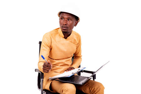 young architect business man wearing white safety helmet sitting on chair with laptop and thinking about what to write on clipboard.の写真素材