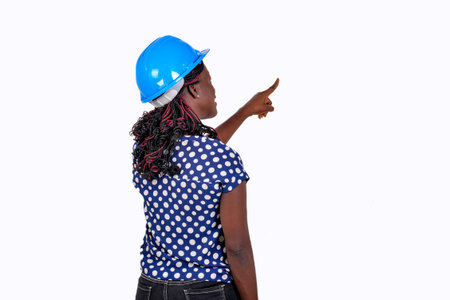 rear view of young female construction engineer pointing finger at empty space.