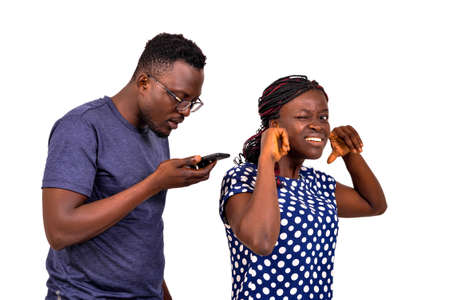 portrait of a jealous young man checking the messages on his girlfriend's mobile phone.の写真素材