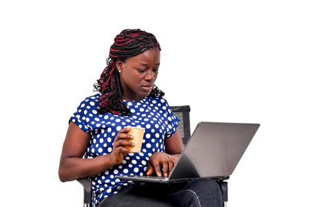 a beautiful businesswoman with braids sitting in a chair at home working using a laptop computer...