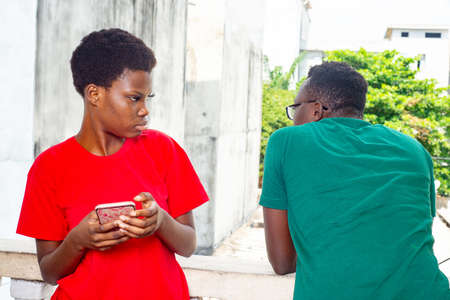 young girl with a mobile phone in hands standing together near her boyfriend on the balcony of the house.の写真素材