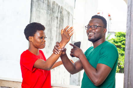 beautiful young couple arguing on the balcony of the house, man holding the hand of his angry girlfriend wanting to hit him.の写真素材