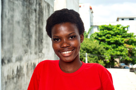 beautiful young girl wearing red t-shirt standing on the balcony of the house while smiling.