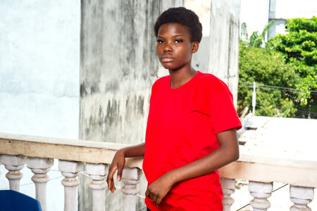 beautiful young girl wearing red t-shirt standing on the balcony of the house.