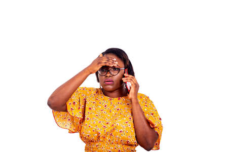 a beautiful businesswoman in eyeglasses standing on white background talking on the cell phone with her hand on her forehead while looking to look away.の写真素材