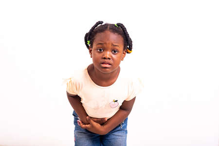 close up of cute little girl standing over white background complaining about stomach ache..の写真素材