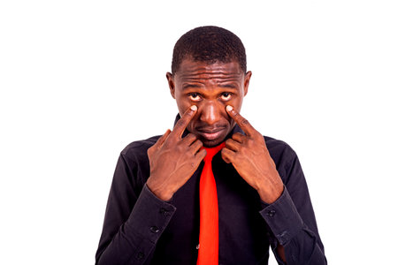 portrait of a handsome young man standing and holding fingers near eyes.の写真素材