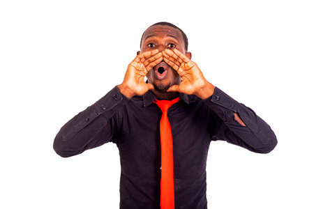 portrait of a handsome young man standing against white background and shouting loud with hands near mouth.の写真素材