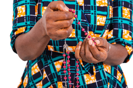 Christian adult woman praying with hands holding rosary beads.の写真素材