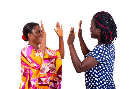 two beautiful women playing a game with hands up while smiling.の写真素材