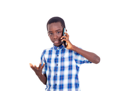 young boy in checkered shirt standing on white background talking on cellphone while making hand gesture.の写真素材