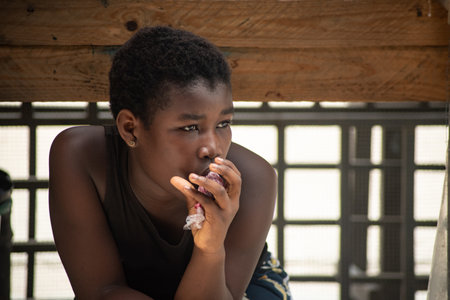 close-up of girl in black tank top sitting on stool and drinking juice.のeditorial素材