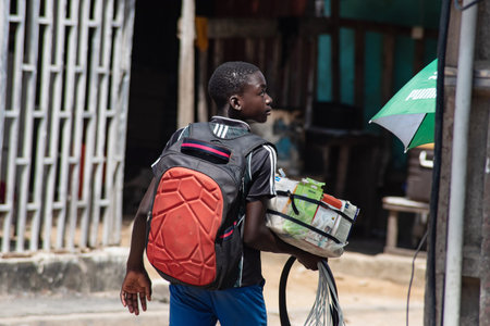 Abidjan, Ivory Coast- March 14, 2022:portrait of young street vendor holding mobile phone accessories and walking through neighborhoods in Abidjan.のeditorial素材