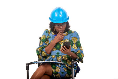 female engineer in traditional dress sitting on chair on white background working using mobile phone and clipboard.の写真素材