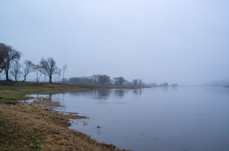 Abandoned place landscape, early morning fog. Calm water, misty lake background.