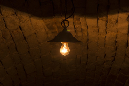 Lightbulb glows with low warm light under the tunnel's ceilingの写真素材