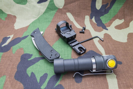 Military set on camouflage background from a flashlight, and the sight of the knife.