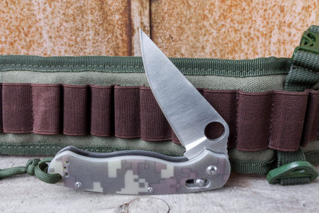 Knife with a hole in the blade. Folding knife on background bandolier. Knife with a knot.