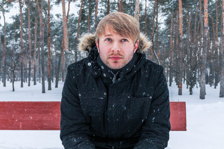 Thoughtful young man. A young man sits on a bench and thinks.の写真素材
