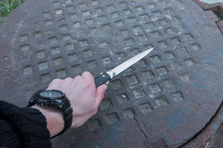 Knife in a man hands. Rusty background. Rotten iron.